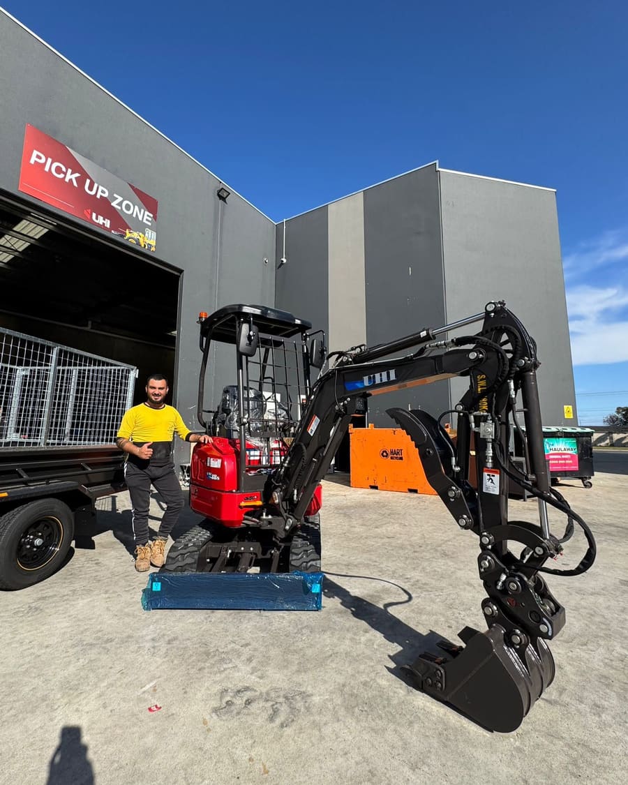The owner of Clear Ground Excavations standing beside his 1.8 tonne mini excavator and tipper trailer.